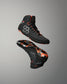 A pair of athletic high-top wrestling shoes floating against a neutral gray gradient background. The shoes are primarily black with vibrant orange accents and a gray geometric hexagonal logo on the side.