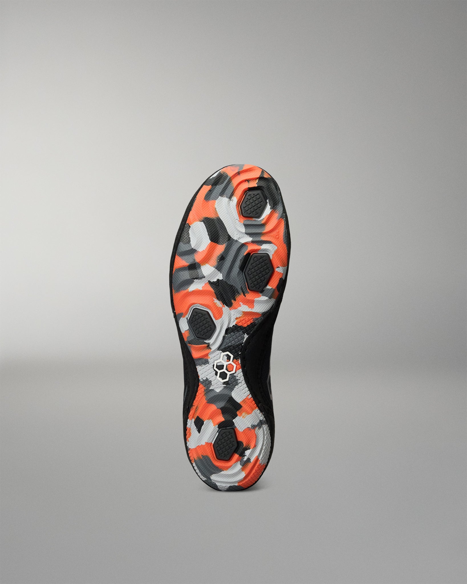 The outsole of a black Wrestling Shoe featuring a vibrant orange, gray, and black camouflage pattern, shown against a neutral gray background.