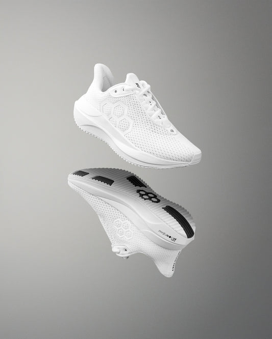 White athletic shoe with brand logo on a reflective gray surface