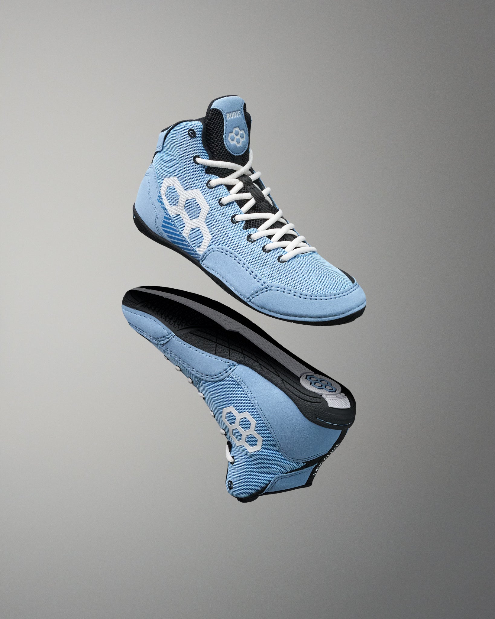 A pair of light blue high-top wrestling shoe shown floating against a gray gradient background, displaying both the side profile and the sole of the shoes.