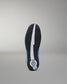 The outsole of a wrestling shoe shown from the bottom, featuring a black textured tread with a central white stripe and a circular blue and white logo near the heel, set against a neutral gray background.