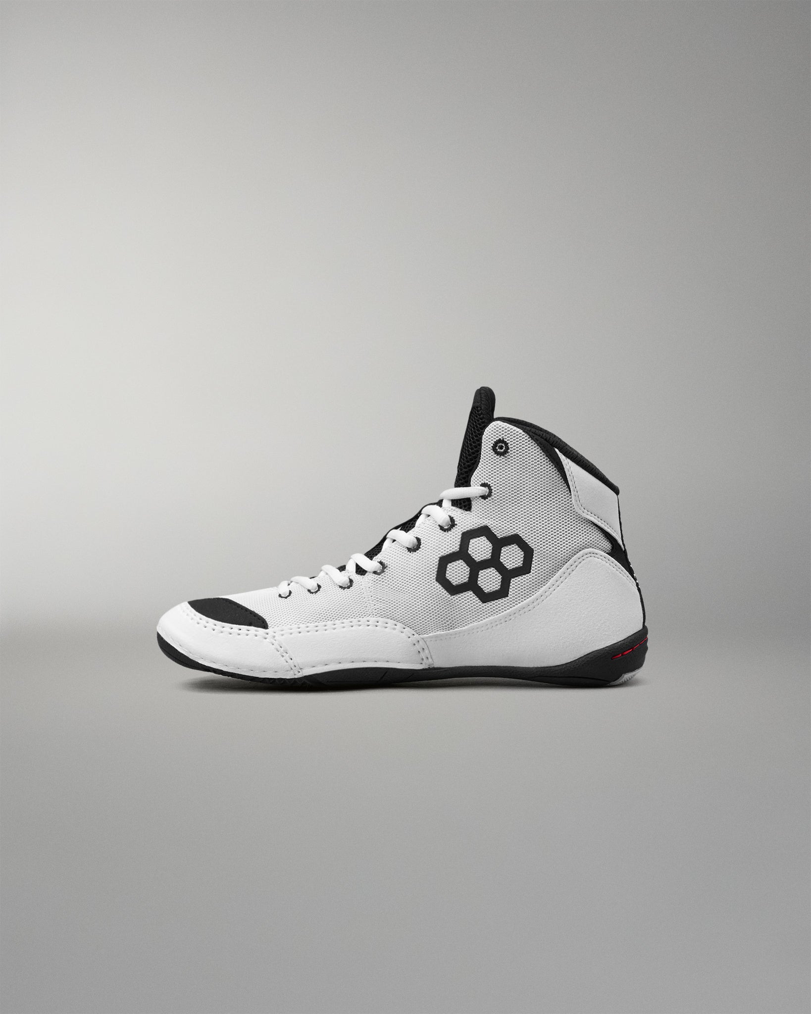 A white high-top wrestling shoe with black accents, including a black geometric logo on the side, black laces, and a black outsole, shown in profile against a neutral gray background.