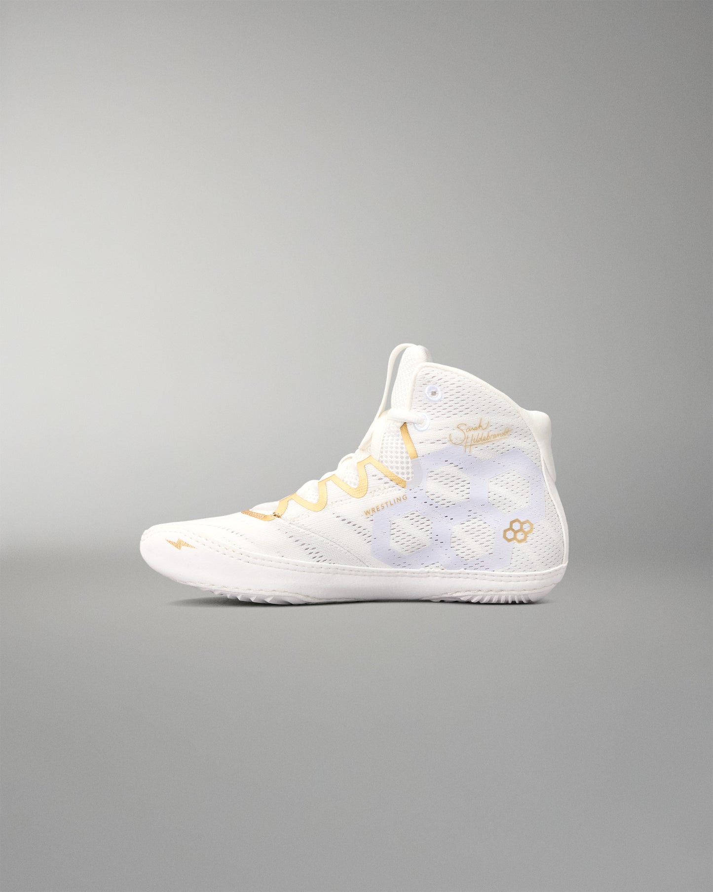 A high-top athletic wrestling shoe in white with gold accents, including the laces and logo details, shown in profile against a neutral gray background.