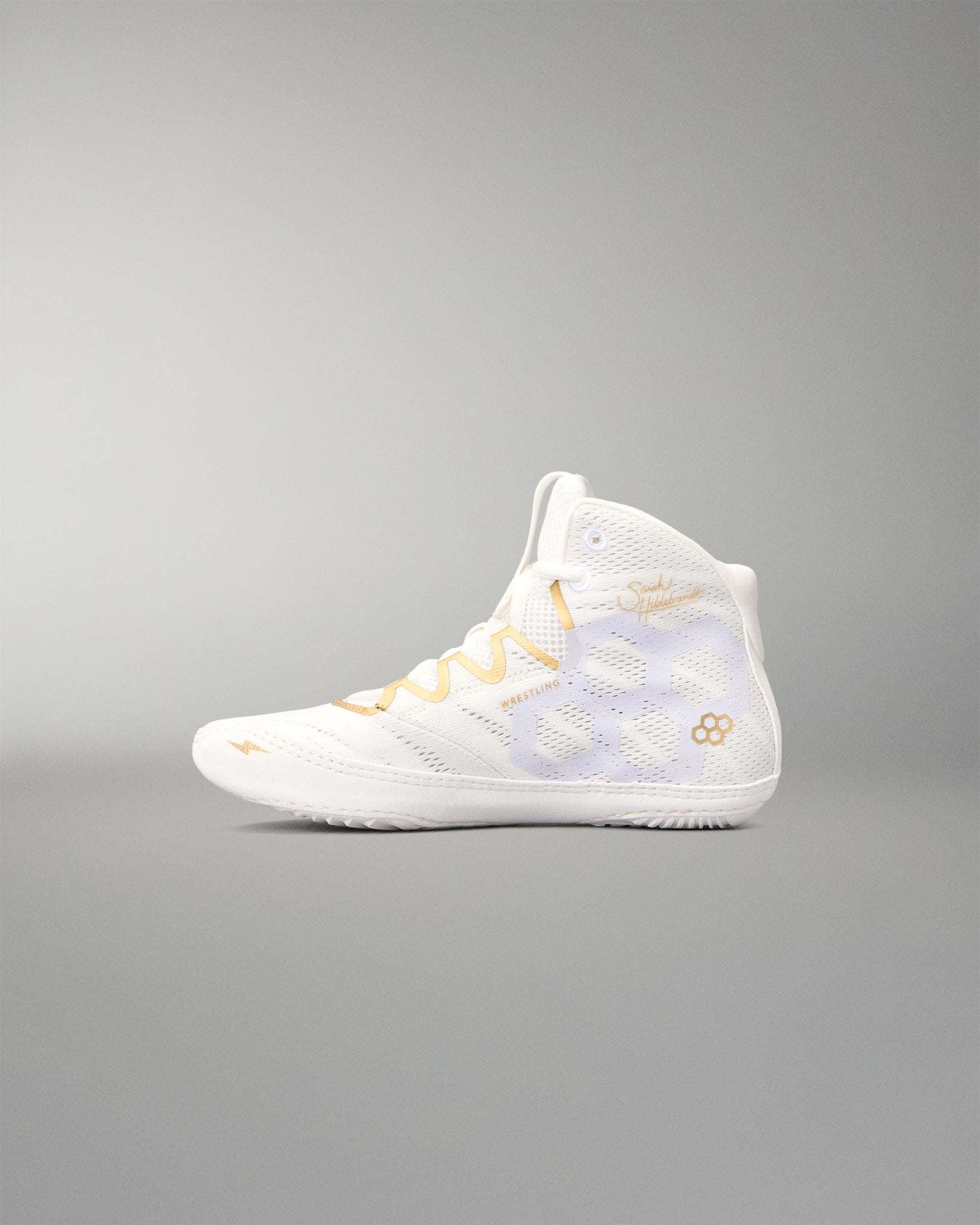 A high-top athletic wrestling shoe in white with gold accents, including the laces and logo details, shown in profile against a neutral gray background.
