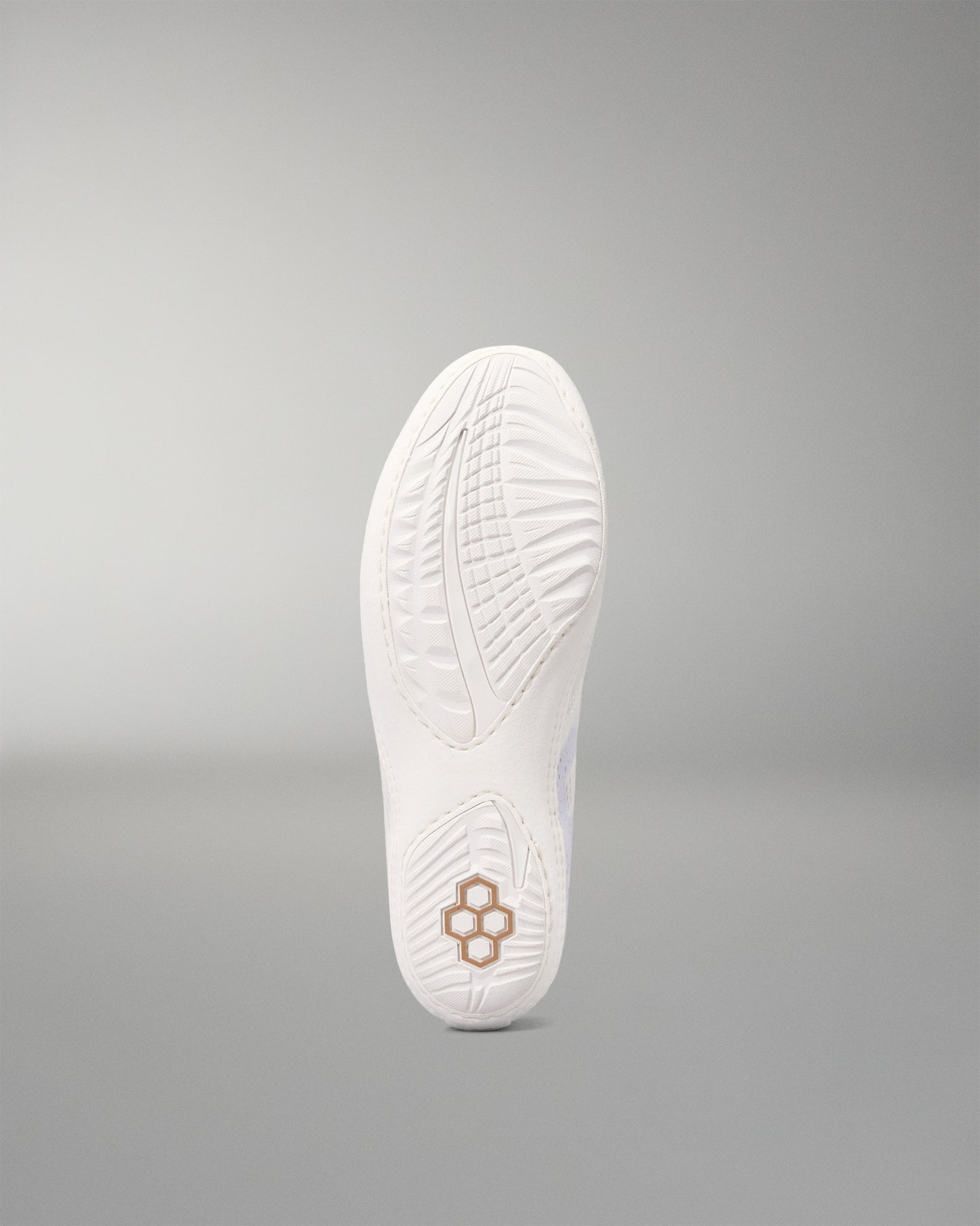 The white outsole of a wrestling shoe, featuring a textured tread pattern and a small geometric logo near the heel, shown against a neutral gray background.