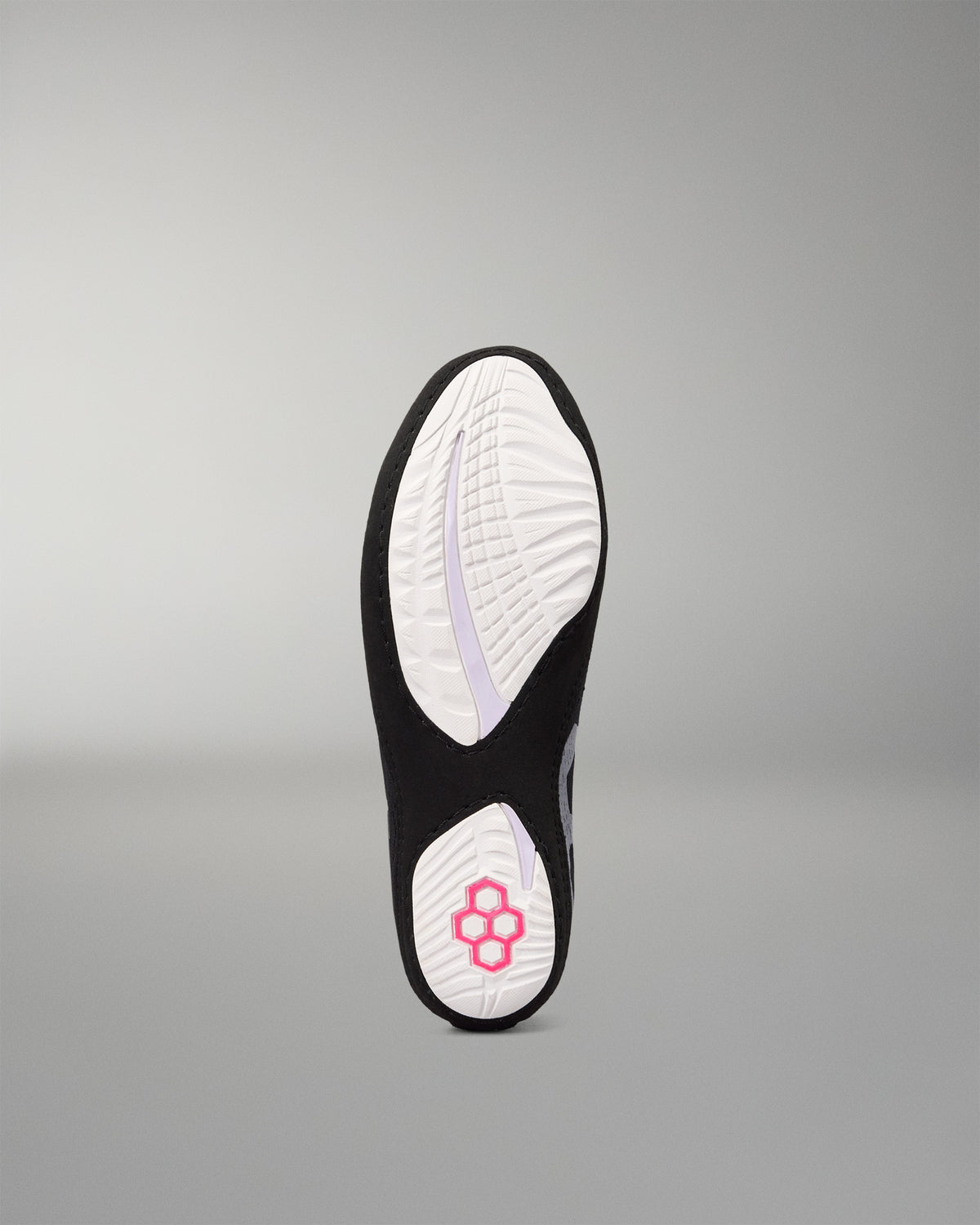 The outsole of a black and white wrestling shoe, featuring a white tread pattern with a pink flower logo on the heel, shown against a neutral gray background.