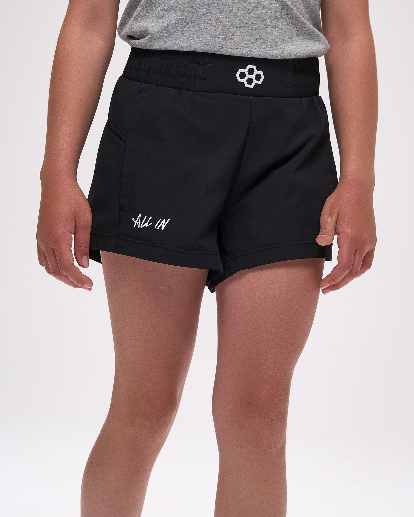 Black athletic shorts with 'All In' text worn by a person on a white background