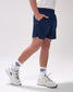 Person wearing navy shorts and white sneakers on a plain background