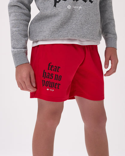 Person wearing red shorts with 'fear has no power' text and a gray sweatshirt on a white background