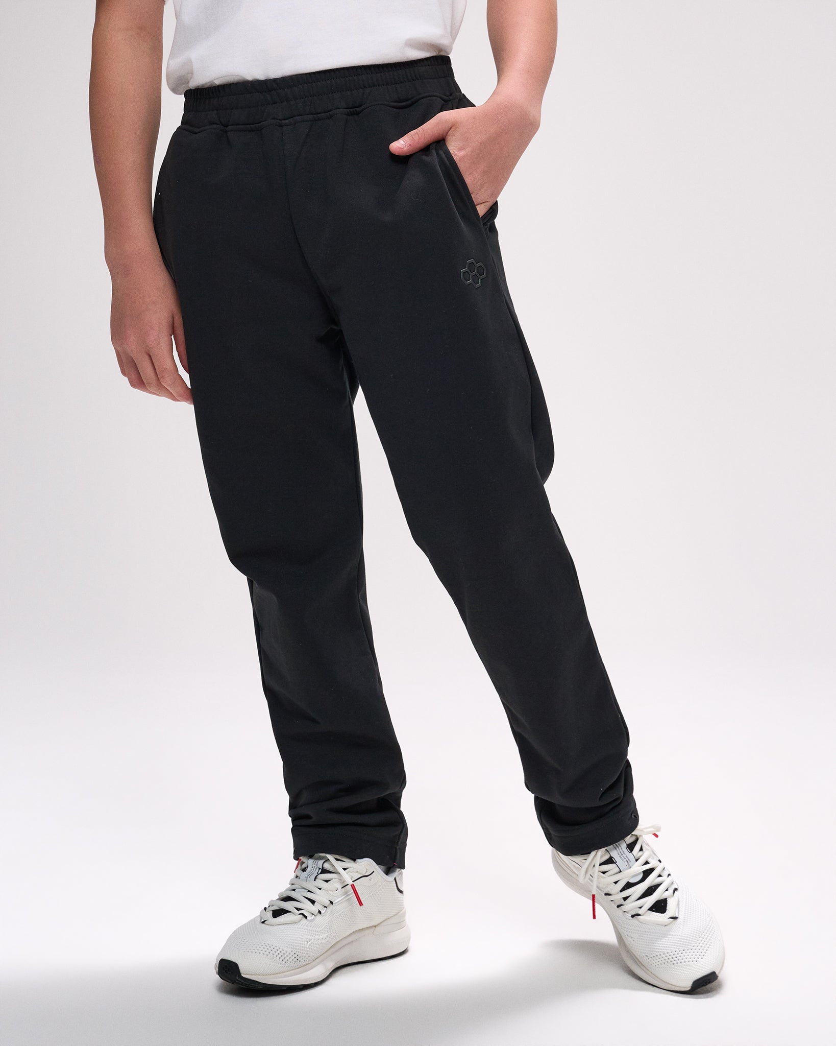 Person wearing black pants and white sneakers on a plain background