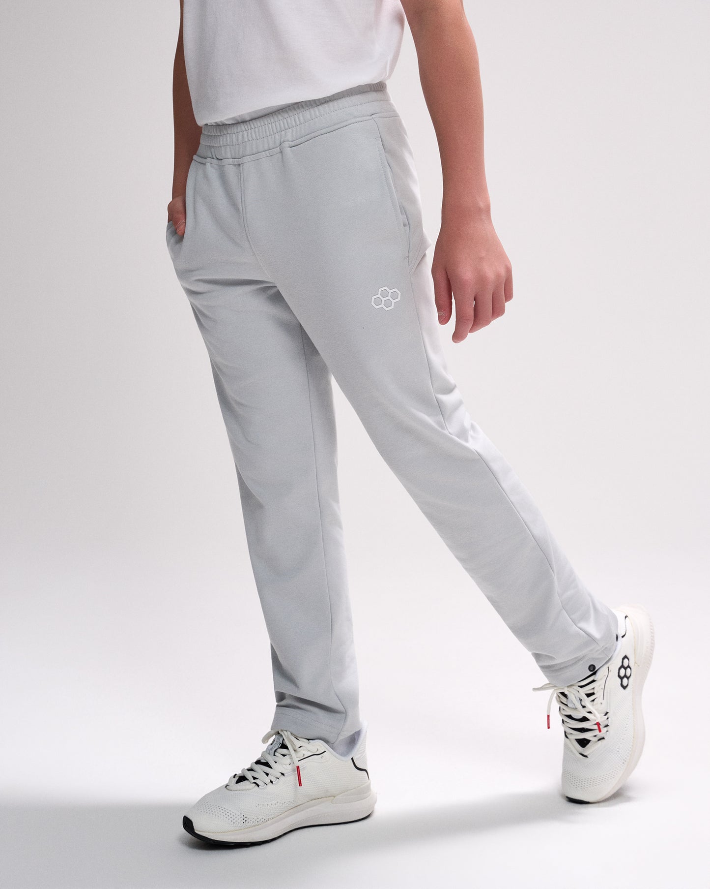 Person wearing light gray pants with a logo on a white background