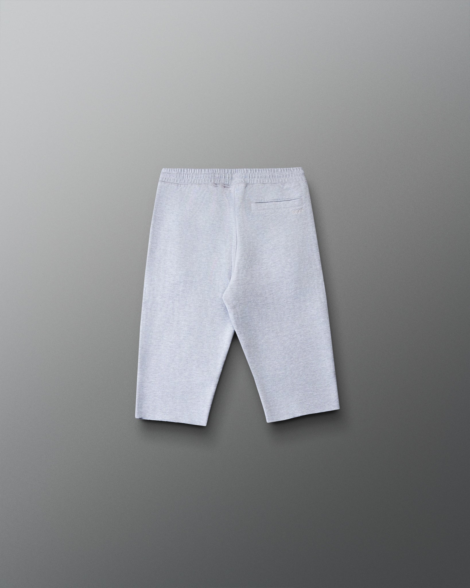 Back view of the RUDIS Youth Titan Heavyweight Cut-Off Sweatpants in heather gray featuring a rear pocket, subtle RUDIS branding, and raw-cut hems.