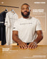 Man wearing a 'Wrestling' t-shirt with text about hybrid fabric and moisture wicking, against a beige background.