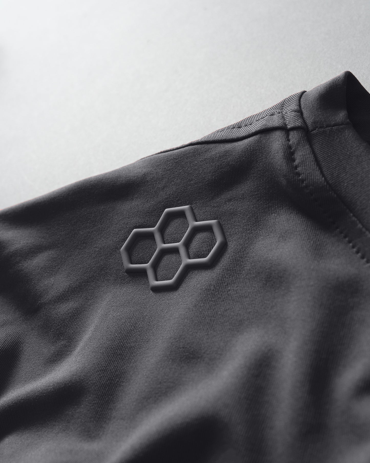 Close-up of a dark fabric with a geometric logo on a light gray background