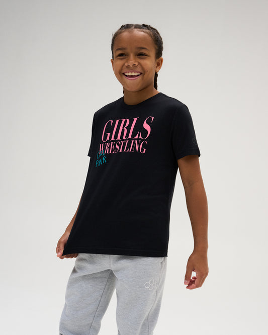Youth athlete models the black RUDIS Girl Power Wrestling Youth Elite Super Soft T-Shirt with pink and teal Girls Wrestling graphic and gray joggers.