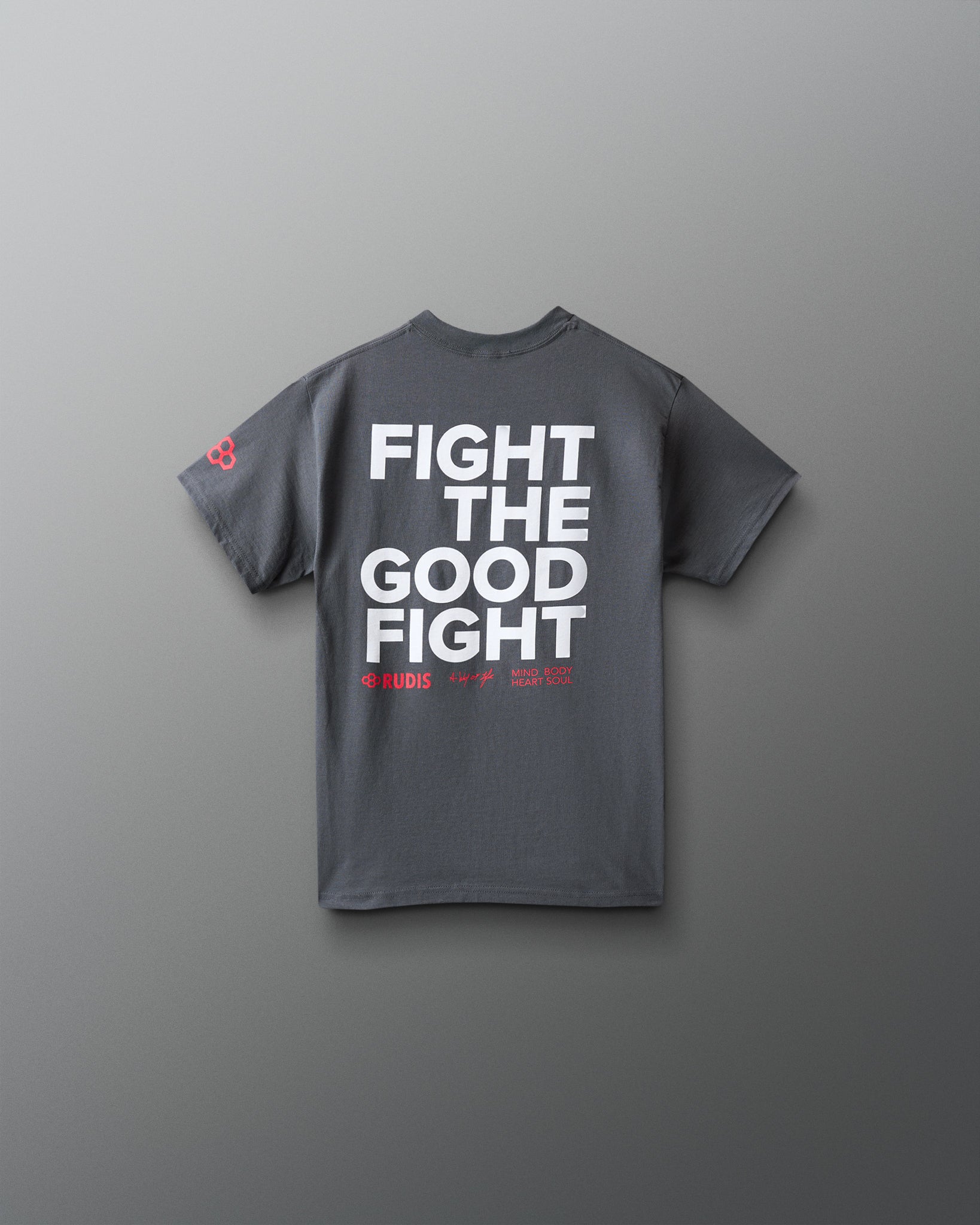 A dark gray short-sleeve t-shirt with bold white text reading 'FIGHT THE GOOD FIGHT' on the back, plus small red text and a small red logo on the left sleeve, shown against a smooth gray background.