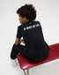 A child wearing a black t-shirt with 'A WAY OF LIFE' printed in white on the back, sitting on a red bench against a white studio background.