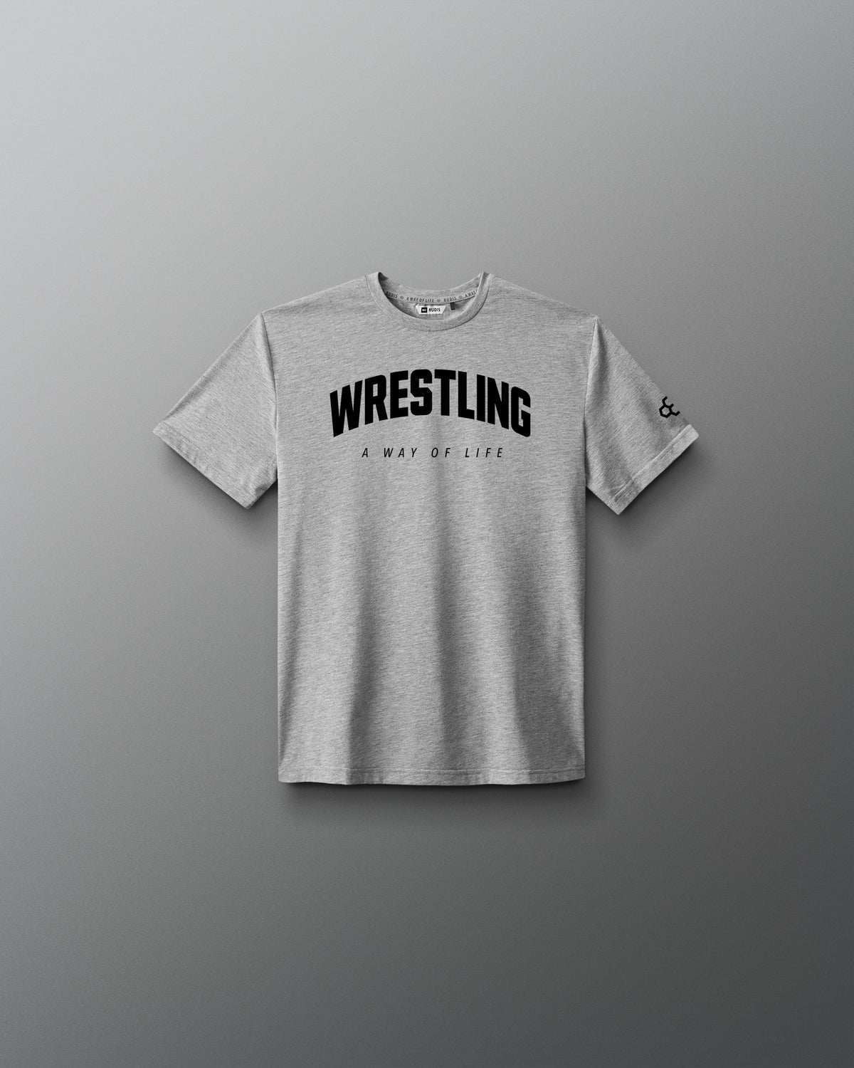 A light gray heather crewneck t-shirt with 'WRESTLING' printed in bold black letters across the chest, with 'A WAY OF LIFE' underneath, displayed on a dark gray gradient background.