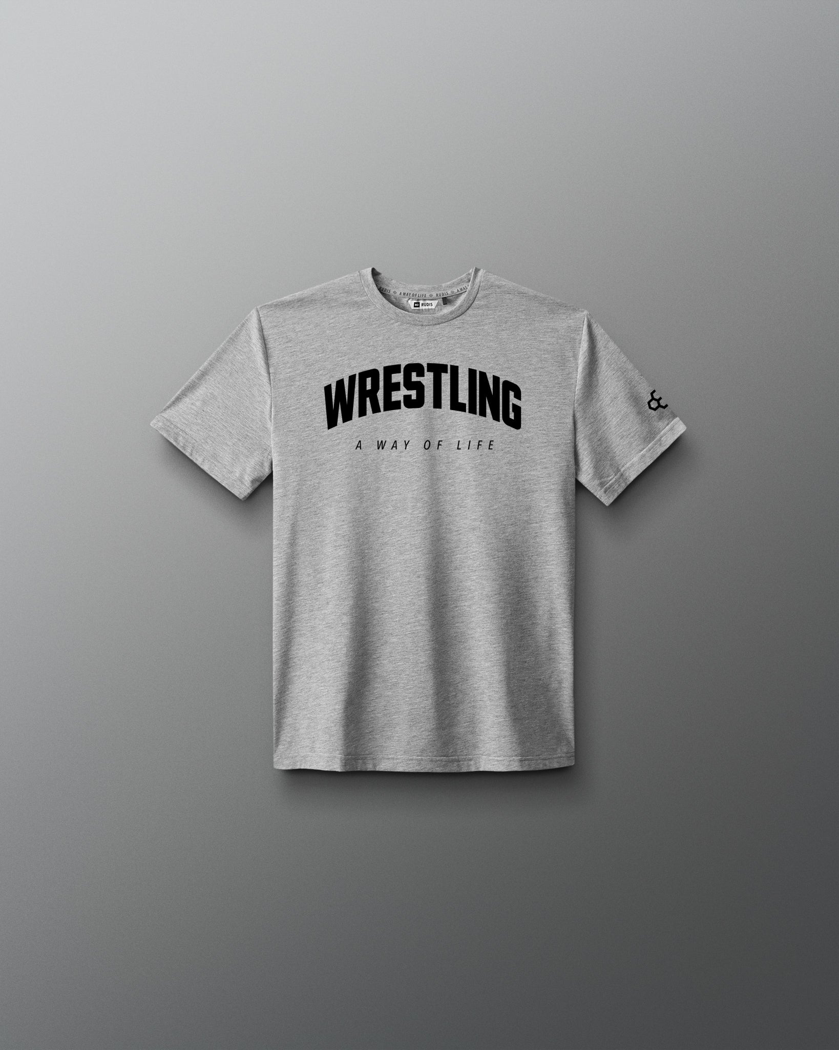 A light gray heather crewneck t-shirt with 'WRESTLING' printed in bold black letters across the chest, with 'A WAY OF LIFE' underneath, displayed on a dark gray gradient background.