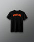 A black short-sleeve crewneck t-shirt with 'WRESTLING' printed in orange arched text and 'A WAY OF LIFE' underneath, displayed against a dark gray gradient background.