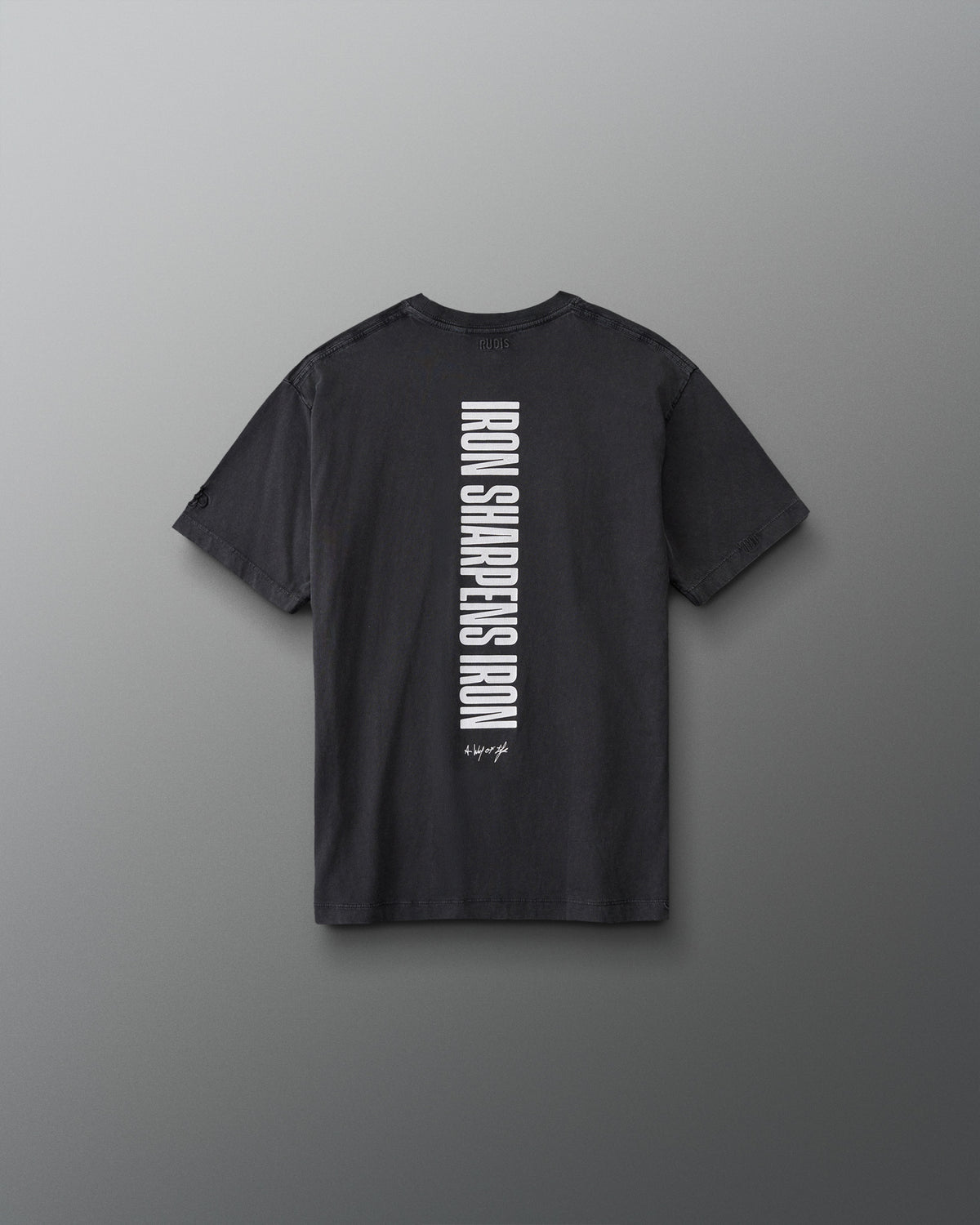 Back view of the RUDIS Iron Sharpens Iron Youth Classic Cotton T-Shirt in Washed Black featuring bold vertical white Iron Sharpens Iron lettering.