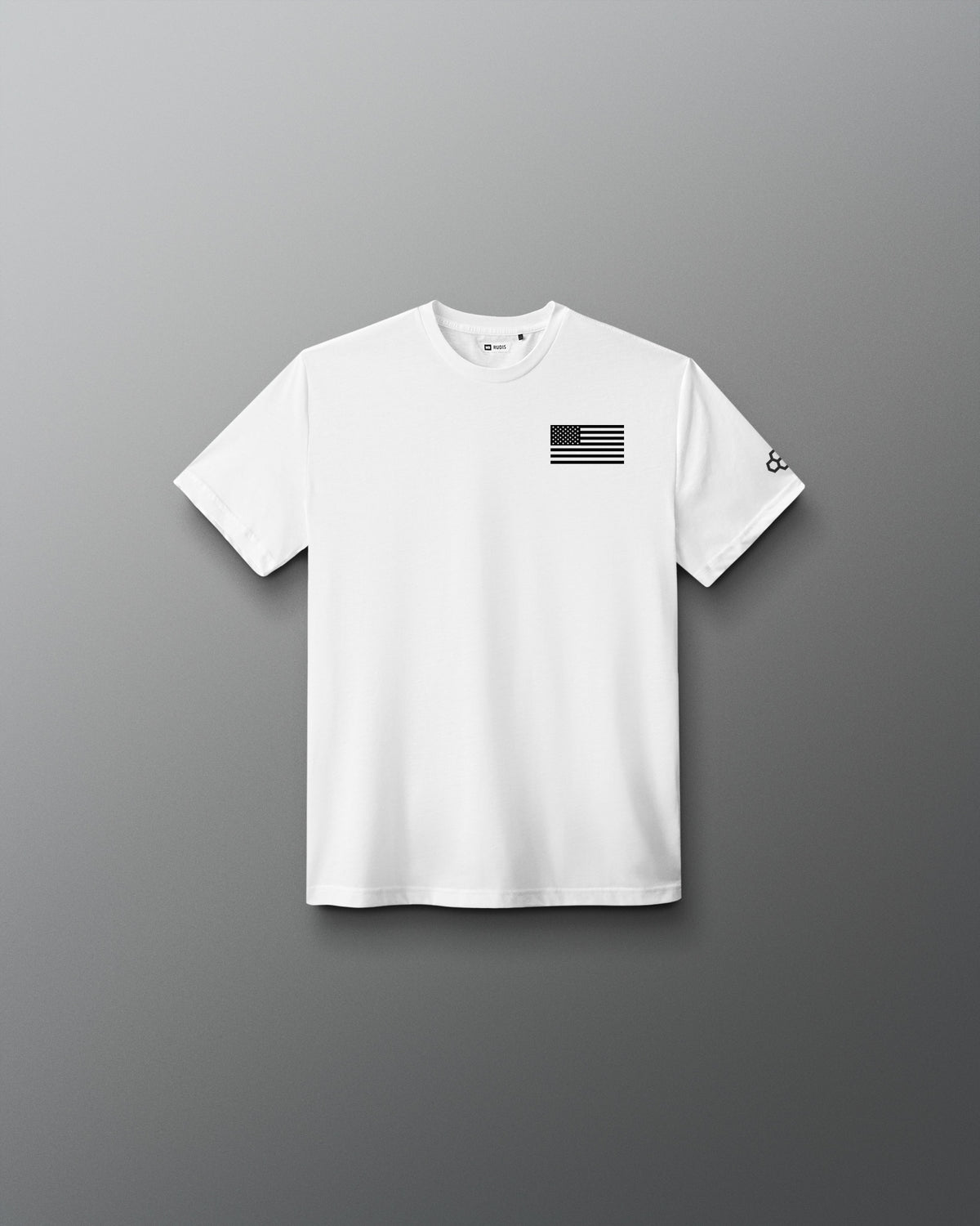 Youth white RUDIS Core Flag Elite Super Soft T-Shirt shown from the front, featuring a black American flag graphic on the left chest and contrasting RUDIS mark on the sleeve.