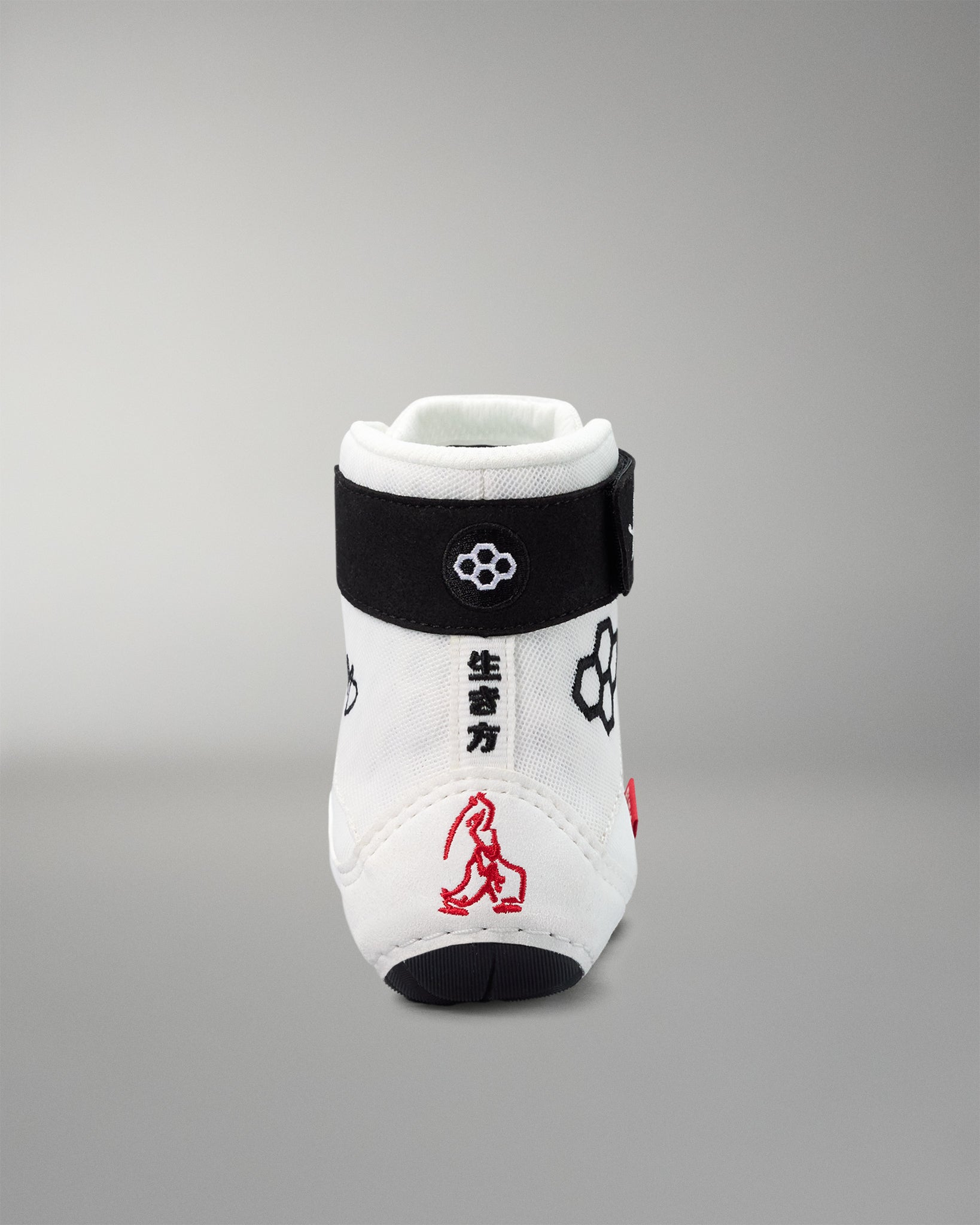 White wrestling shoe with black band and red design on a gray background