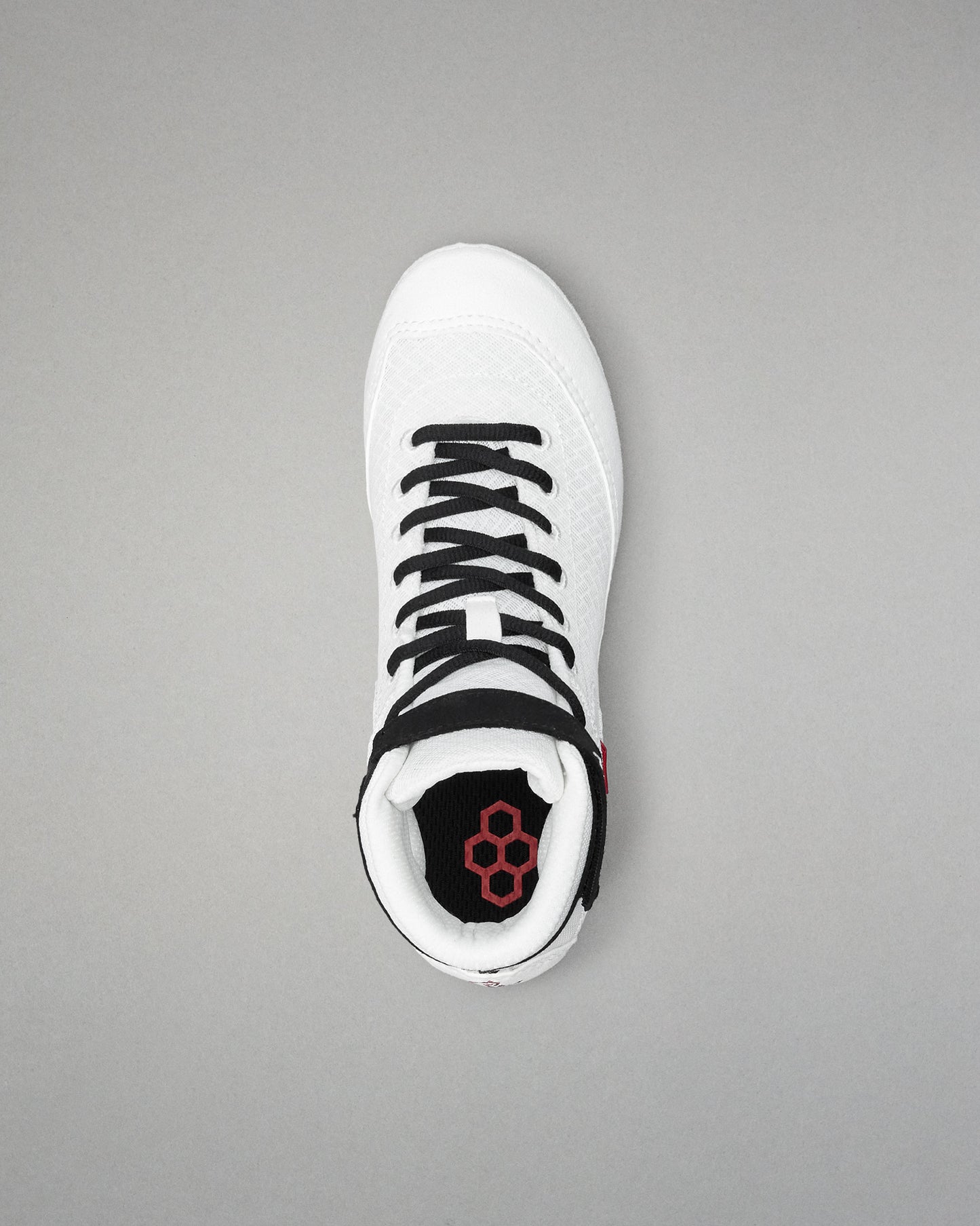 White wrestling shoe with black laces on a gray background