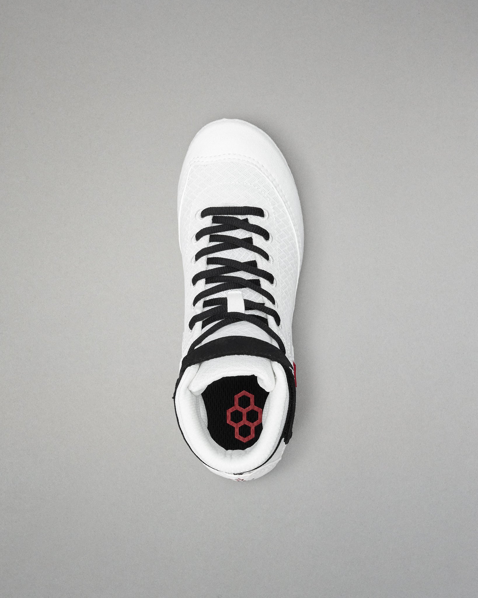 White wrestling shoe with black laces on a gray background