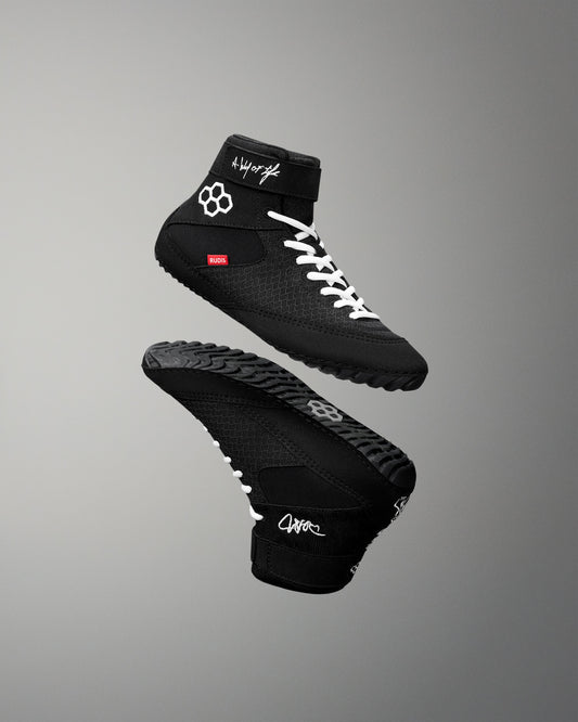 Black wrestling shoes with white laces on a gray background