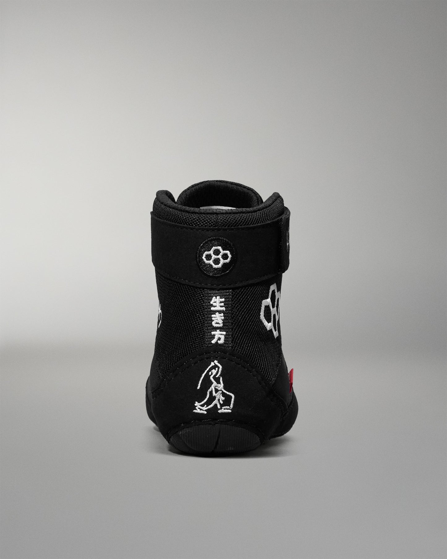Black wrestling shoe with white designs on a gray background