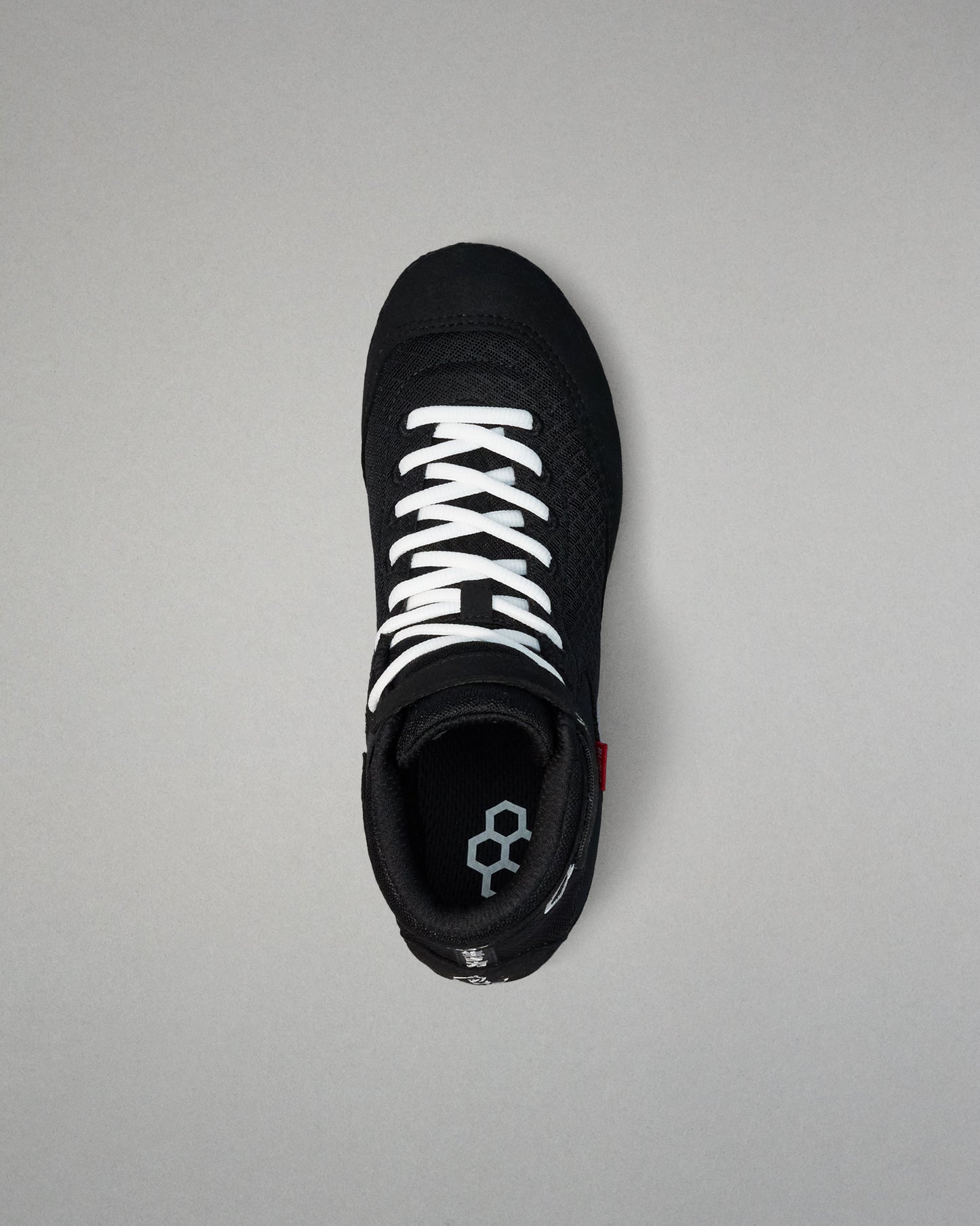 Black wrestling shoe with white laces on a gray background
