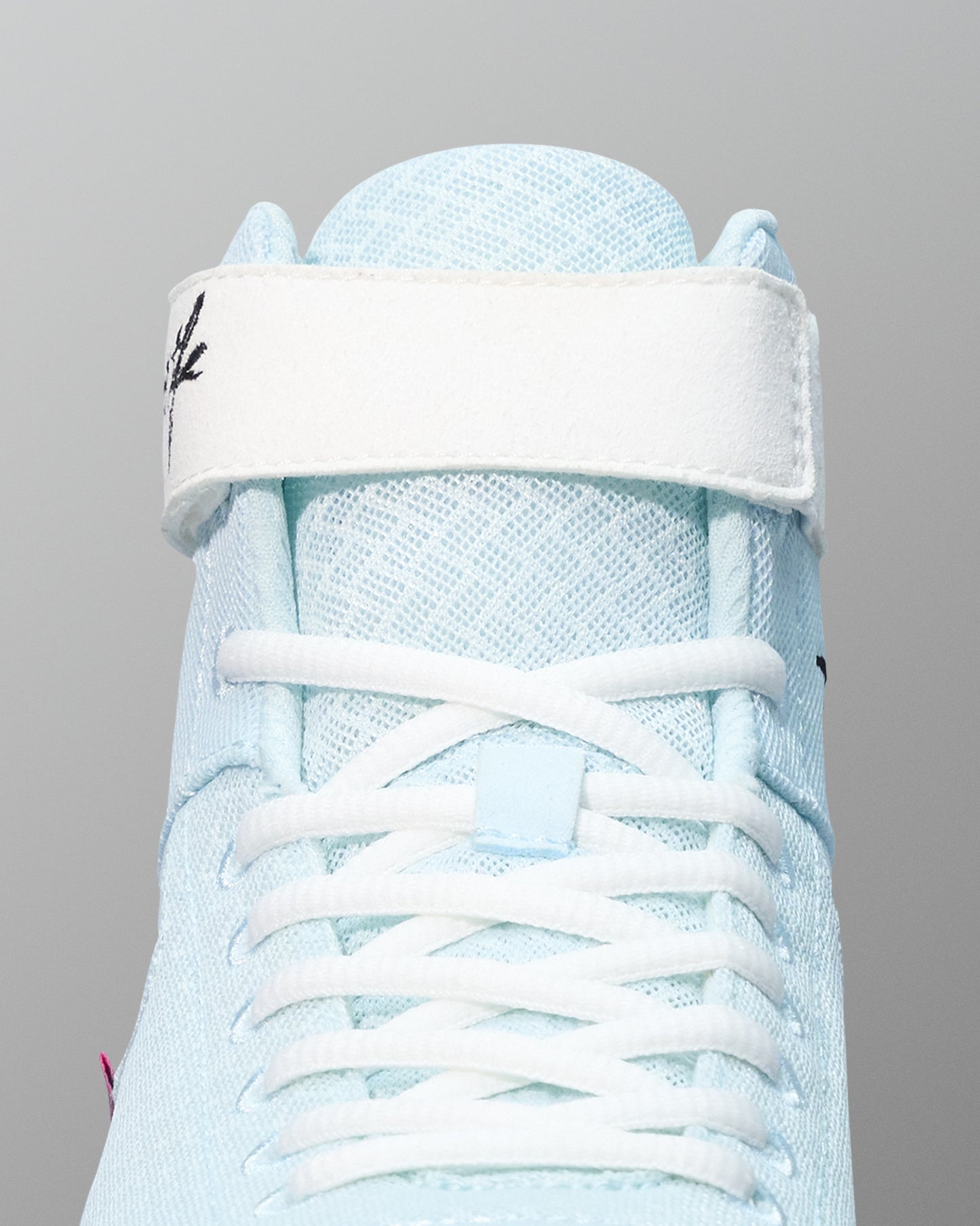 Light blue wrestling shoe with white laces on a gray background