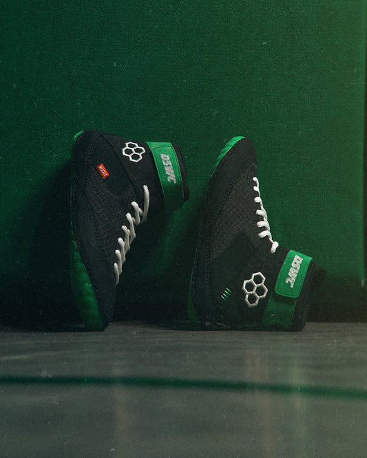 Black and green wrestling shoe with brand logos on a green background