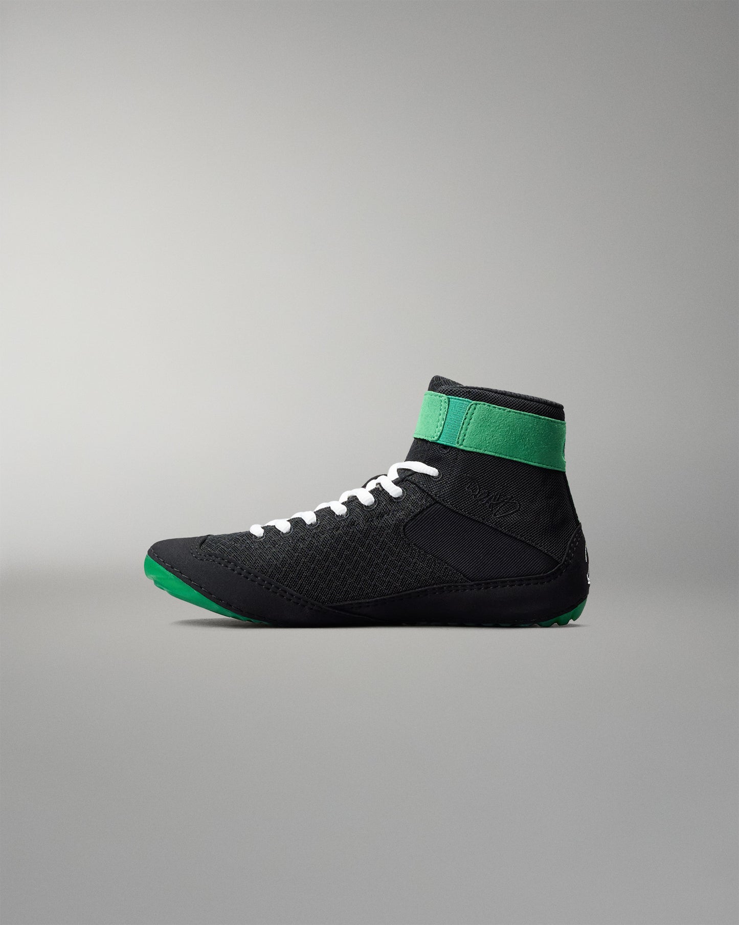 Black wrestling shoe with green accents on a gray background