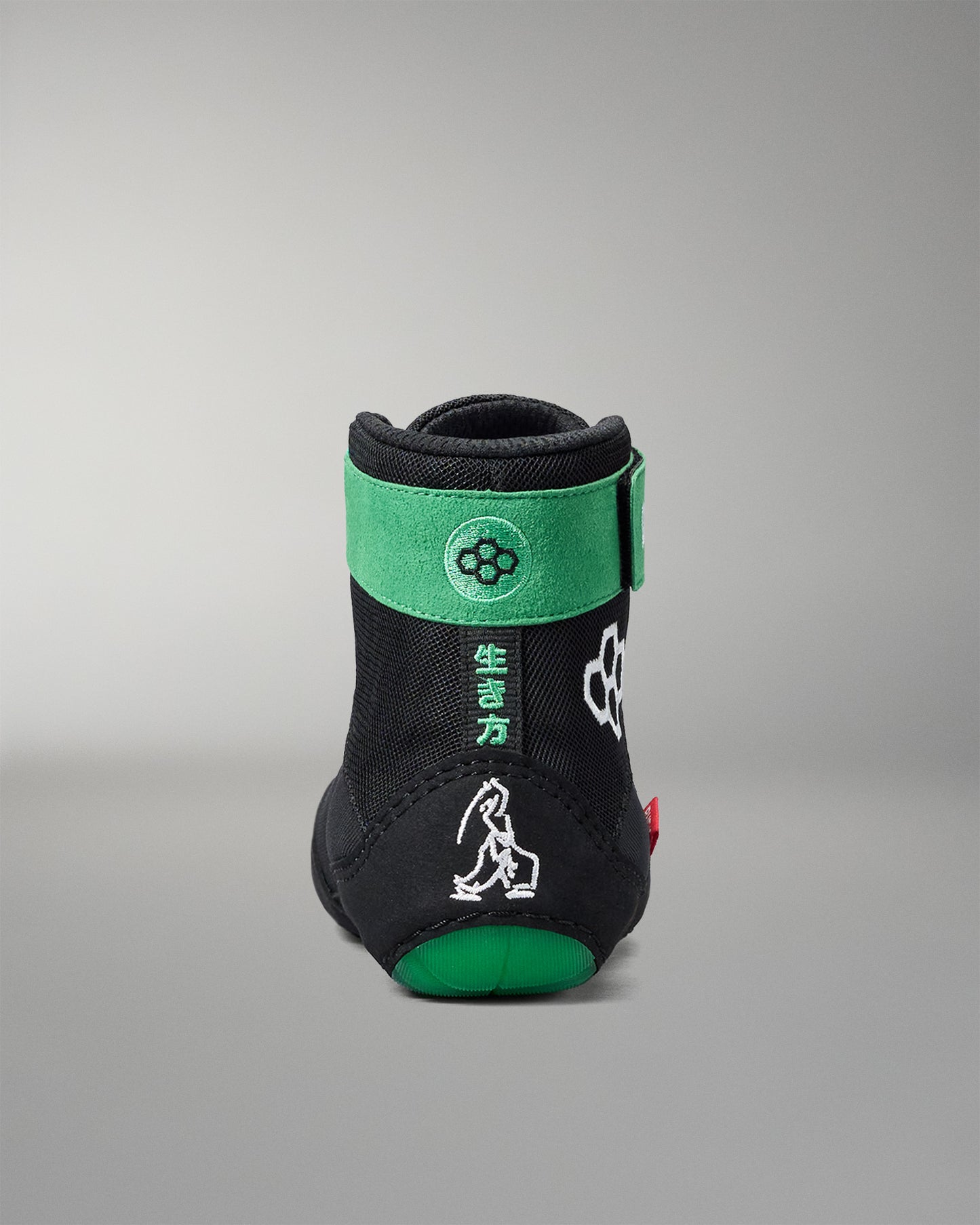 Black and green wrestling shoe with brand logo on a gray background