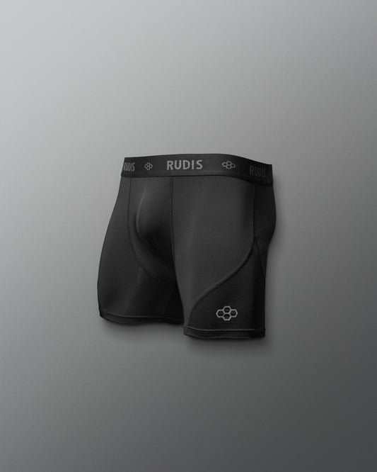 Black athletic shorts with 'RUDIS' branding on a gray background