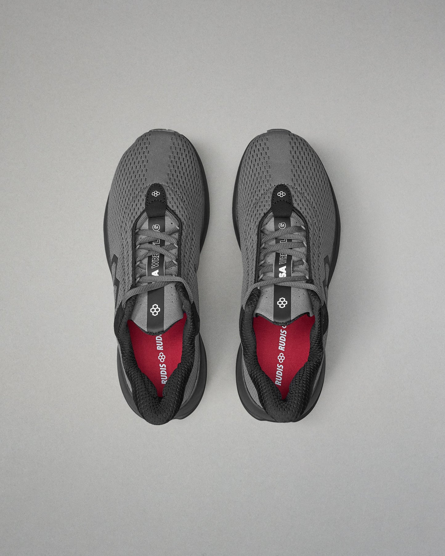 Pair of gray athletic shoes with red lining on a gray background