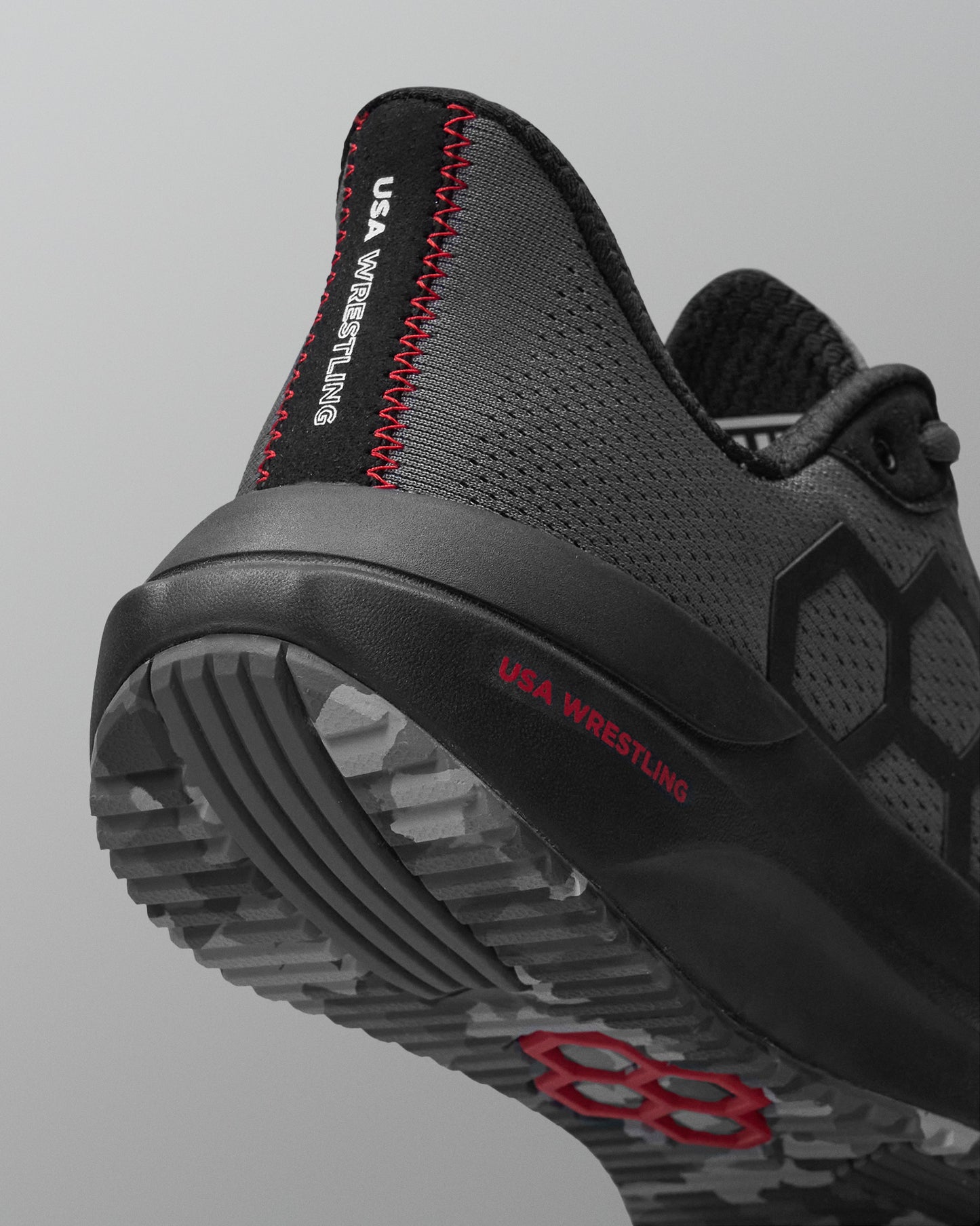 Black and gray wrestling shoe with red accents on a light gray background