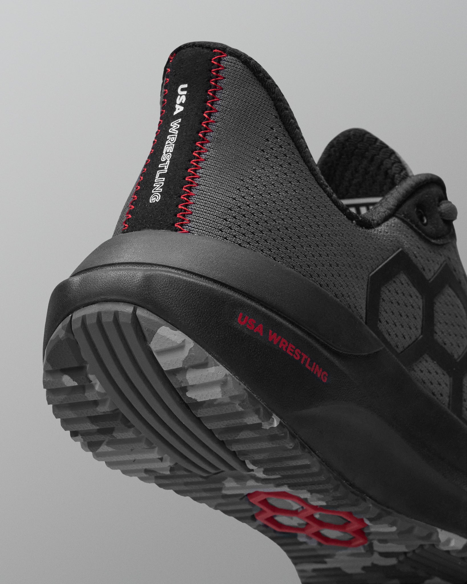 Black and gray wrestling shoe with red accents on a light gray background