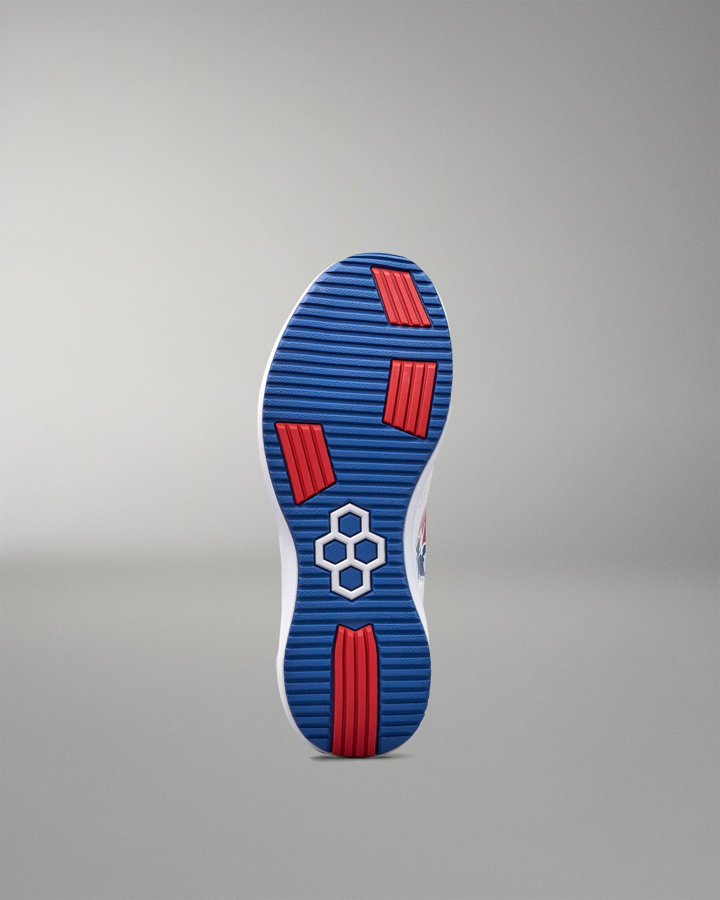 Blue and red sole of a shoe with a hexagonal pattern on a gray background