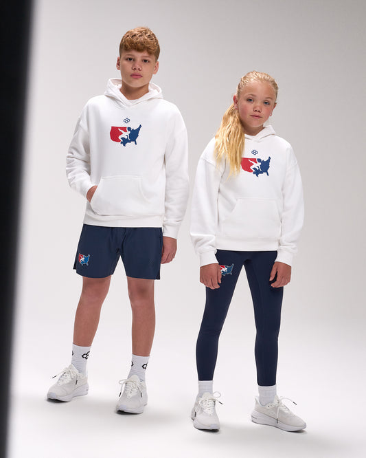 Two children wearing matching white hoodies with a logo, standing side by side on a plain background.