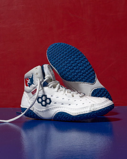 White and blue wrestling shoe with a red background