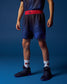 Person wearing blue athletic shorts with a red waistband on a blue background