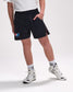 Person wearing black shorts with logos and white sneakers on a light gray background
