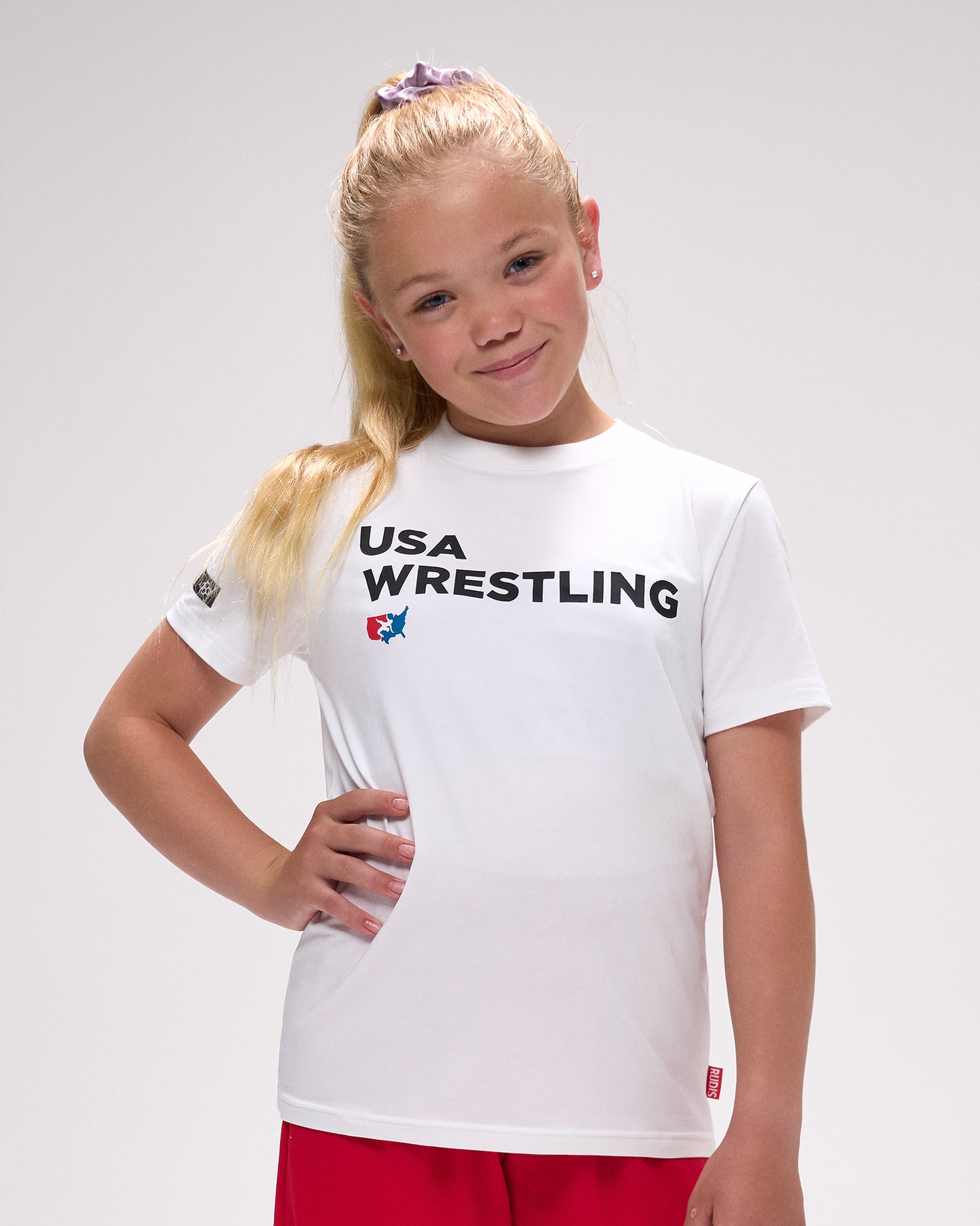 Young girl wearing a USA Wrestling t-shirt on a plain background