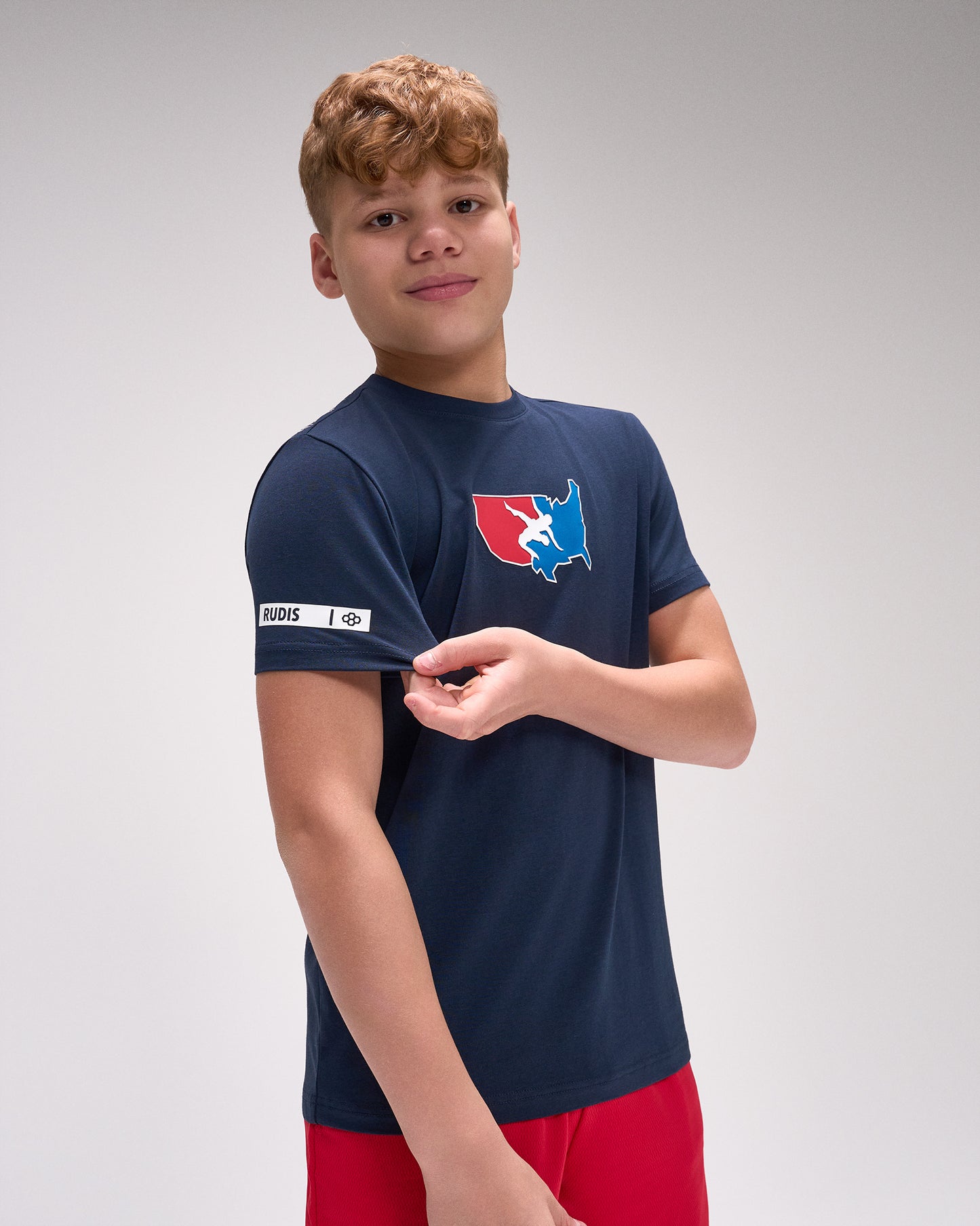 Young boy wearing a navy blue t-shirt with a logo on a gray background