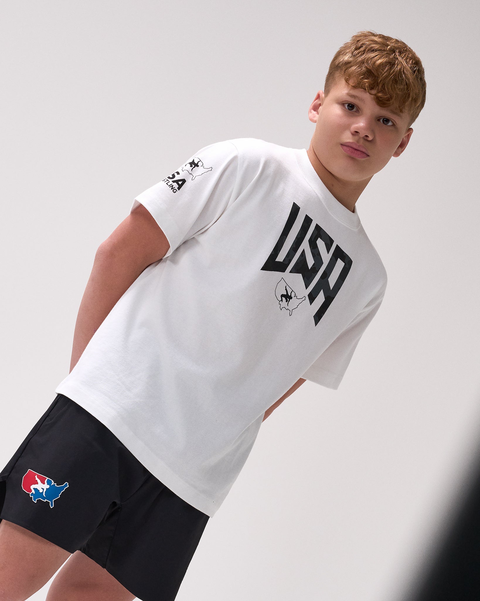 Person wearing a white t-shirt with 'USA' text and black shorts on a light gray background