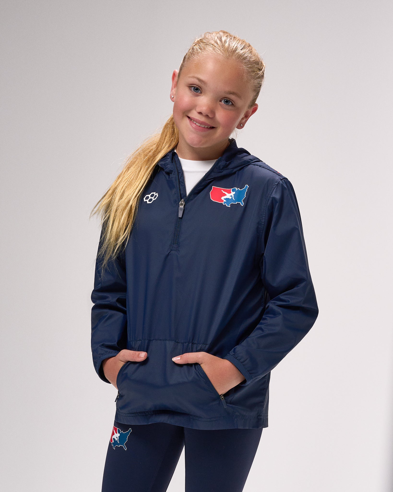 Child wearing a navy blue jacket with a logo on a gray background