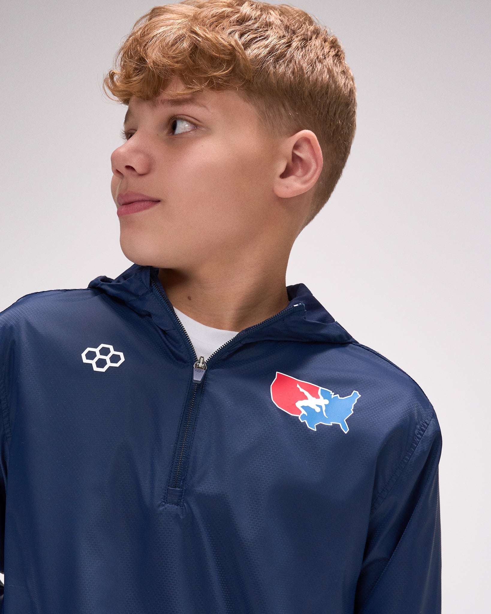 Person wearing a blue jacket with logos on a gray background